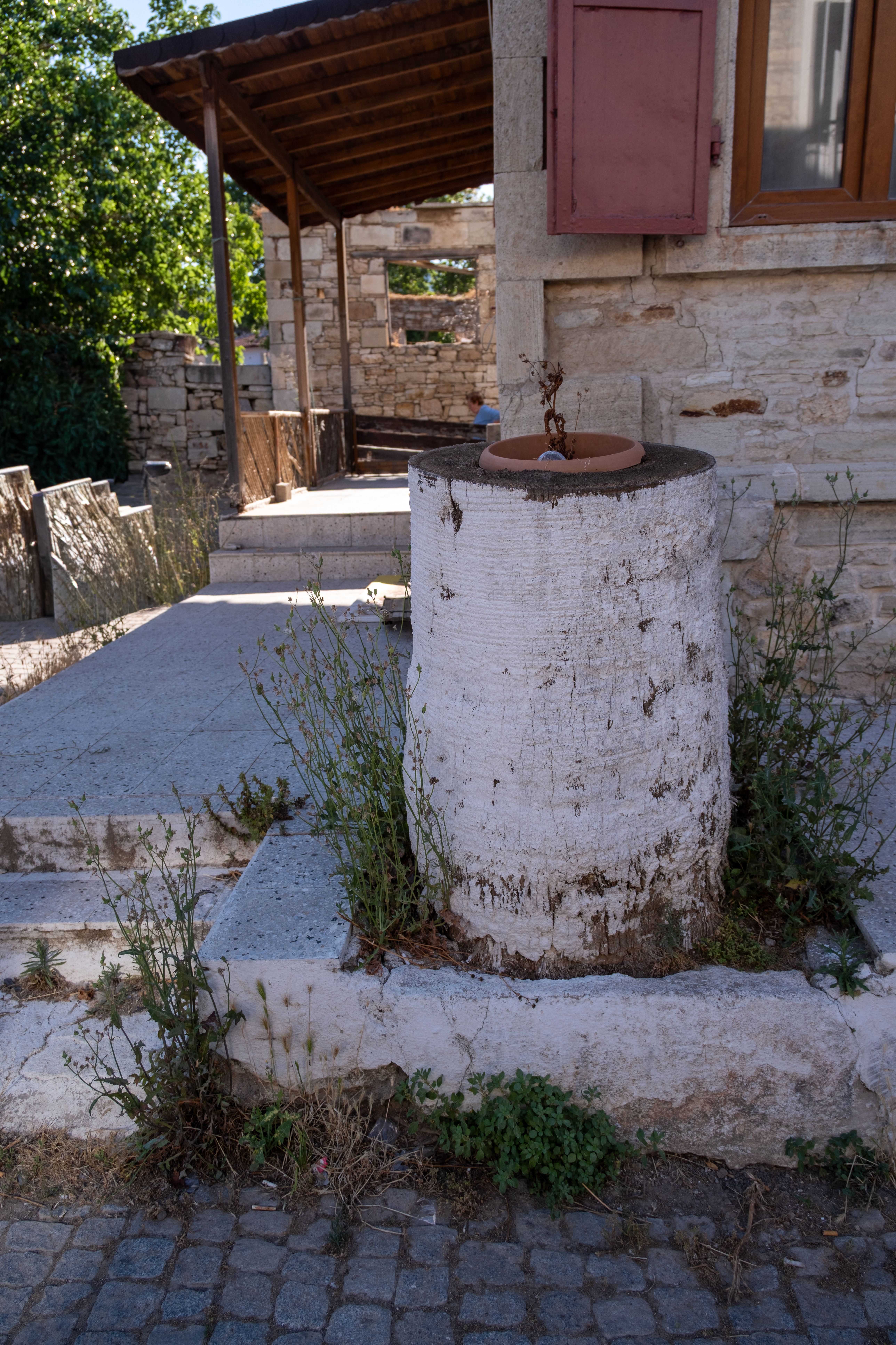A vintage stone fountain near a rustic building in Foça, İzmir, Türkiye.