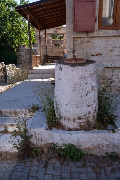 Free A vintage stone fountain near a rustic building in Foça, İzmir, Türkiye. Stock Photo