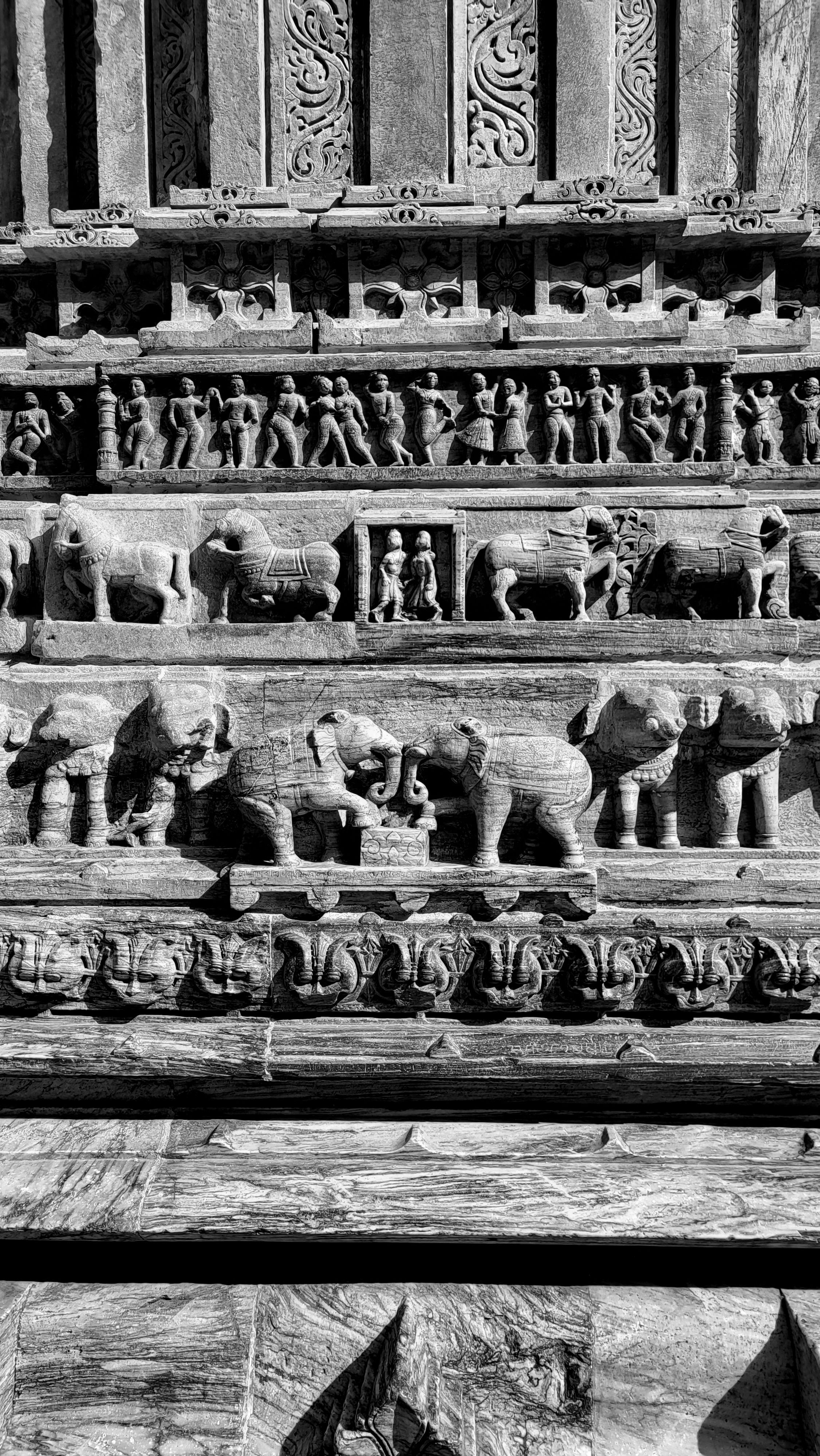 Black and white photo of detailed stone carvings depicting elephants and figures at a Udaipur temple.