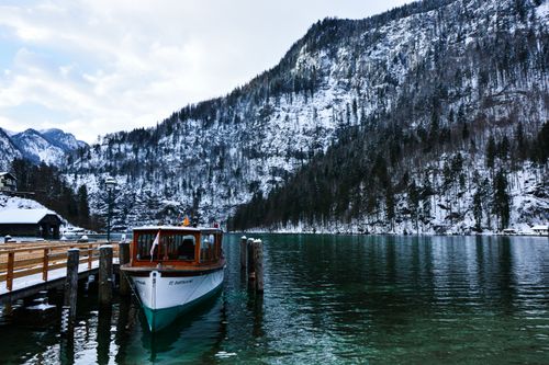 Free Boat docked by the snowy shores of Königssee, Bavaria, showcasing serene winter beauty. Stock Photo
