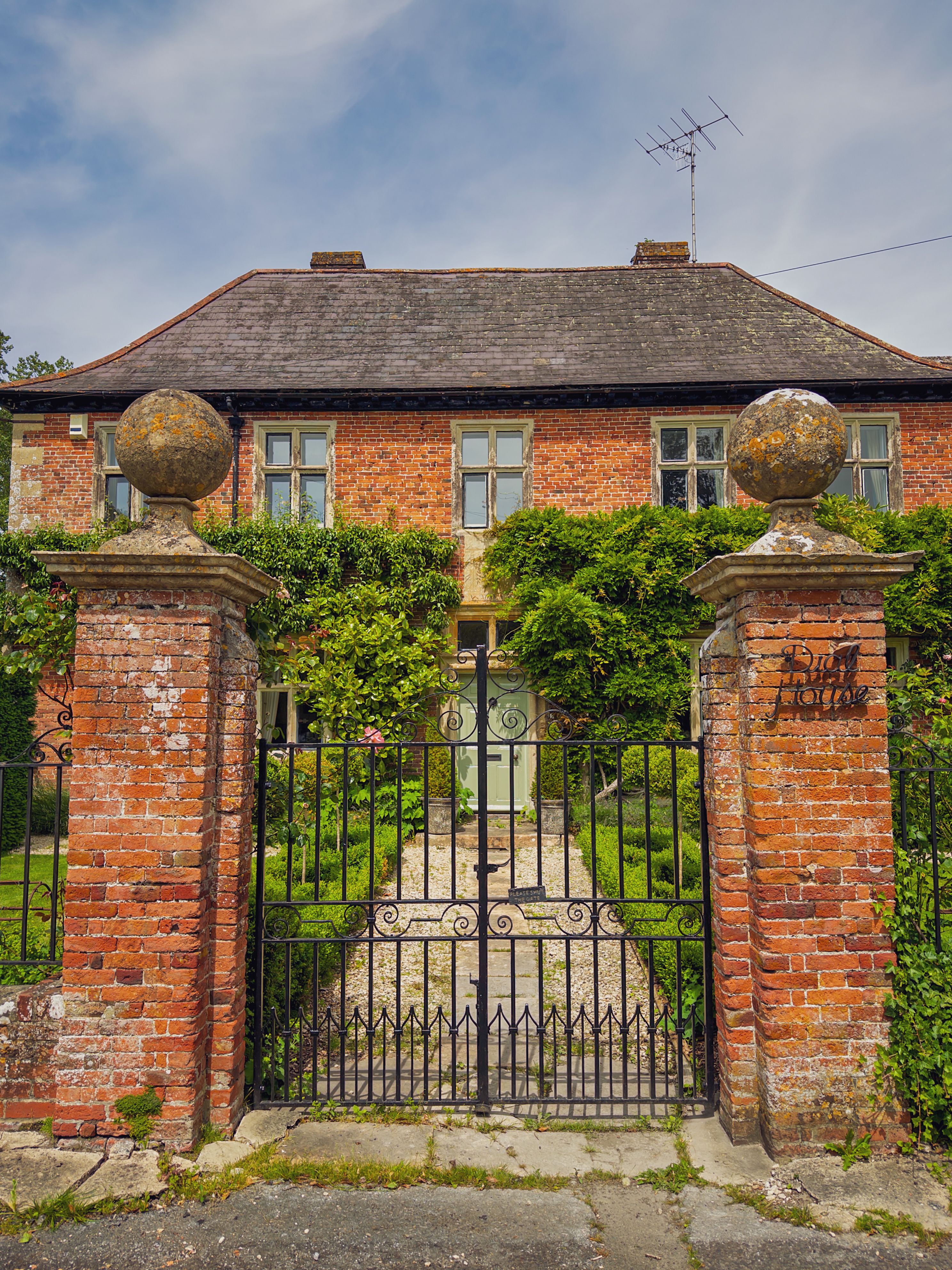 Picturesque brick facade with lush greenery at an English country home in West Lavington.