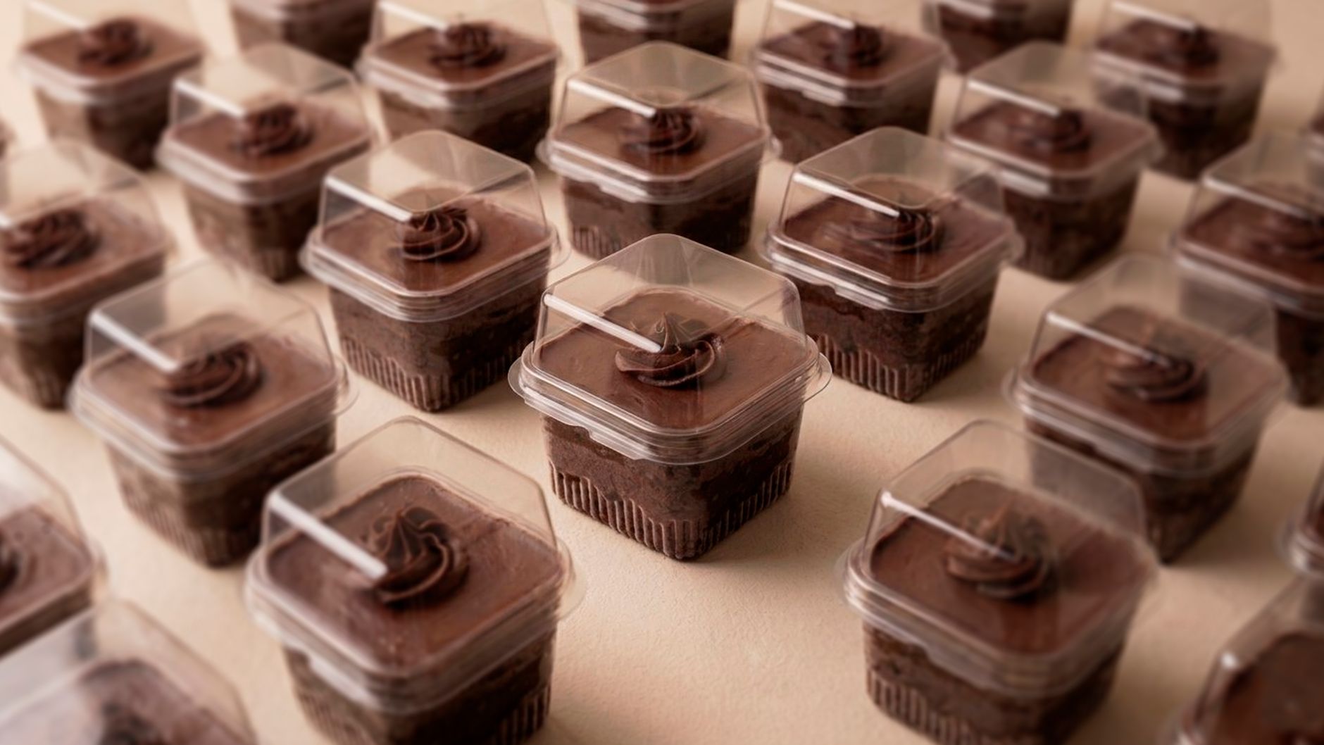 Rows of delicious chocolate cupcakes in clear plastic containers.
