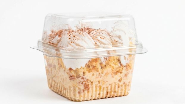 A delectable tiramisu dessert elegantly packed in a clear plastic container, showcasing its creamy layers.
