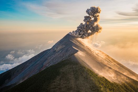 A breathtaking aerial view capturing Fuego Volcano erupting in Sacatepéquez, Guatemala at sunrise.