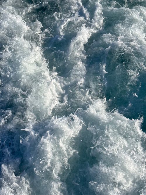Free Aerial view of turbulent ocean waves in motion under sunlight. Captures the dynamic, powerful flow and texture of the sea. Stock Photo