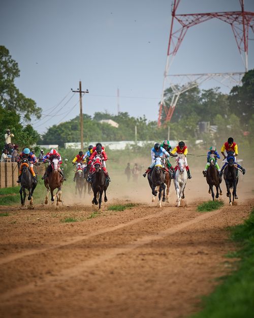 Free Exciting horse race with jockeys competing on a dirt track under cloudy skies. Stock Photo