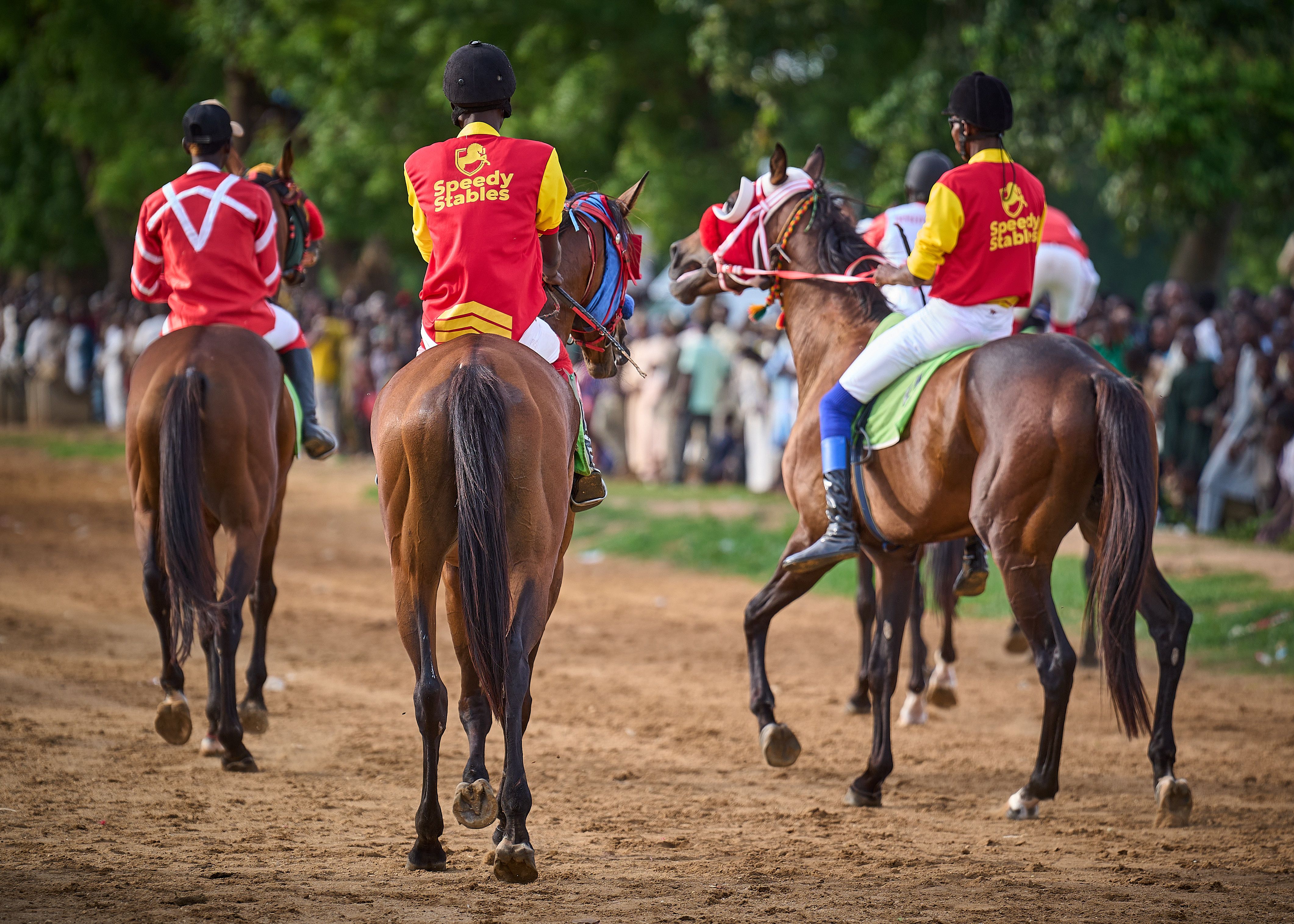 Colorful horse race featuring jockeys in vivid attire on a sunny day.