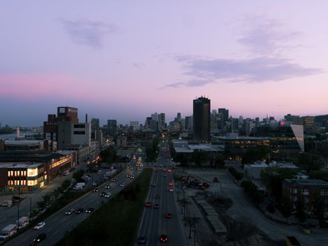 A stunning view of Montreal's skyline at sunset, featuring busy urban streets with cars and iconic buildings.
