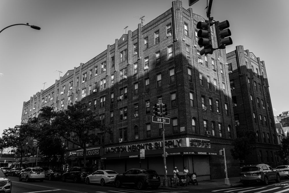 Black and white photo of urban architecture in Jackson Heights, New York City with street life.