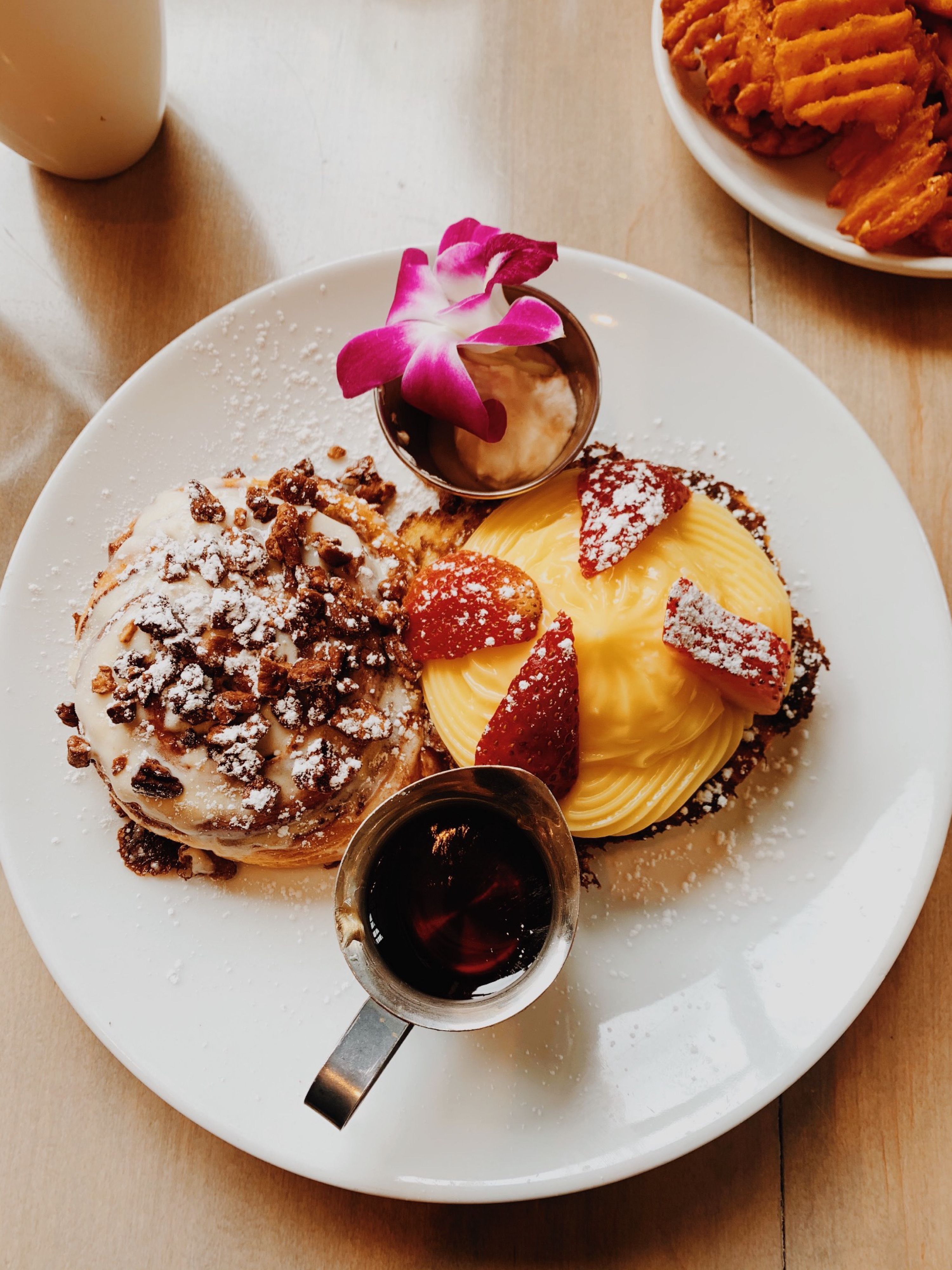 Delicious breakfast featuring gourmet pastry with fresh fruit and syrup on a plate.