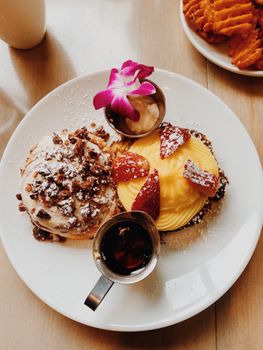 Delicious breakfast featuring gourmet pastry with fresh fruit and syrup on a plate.