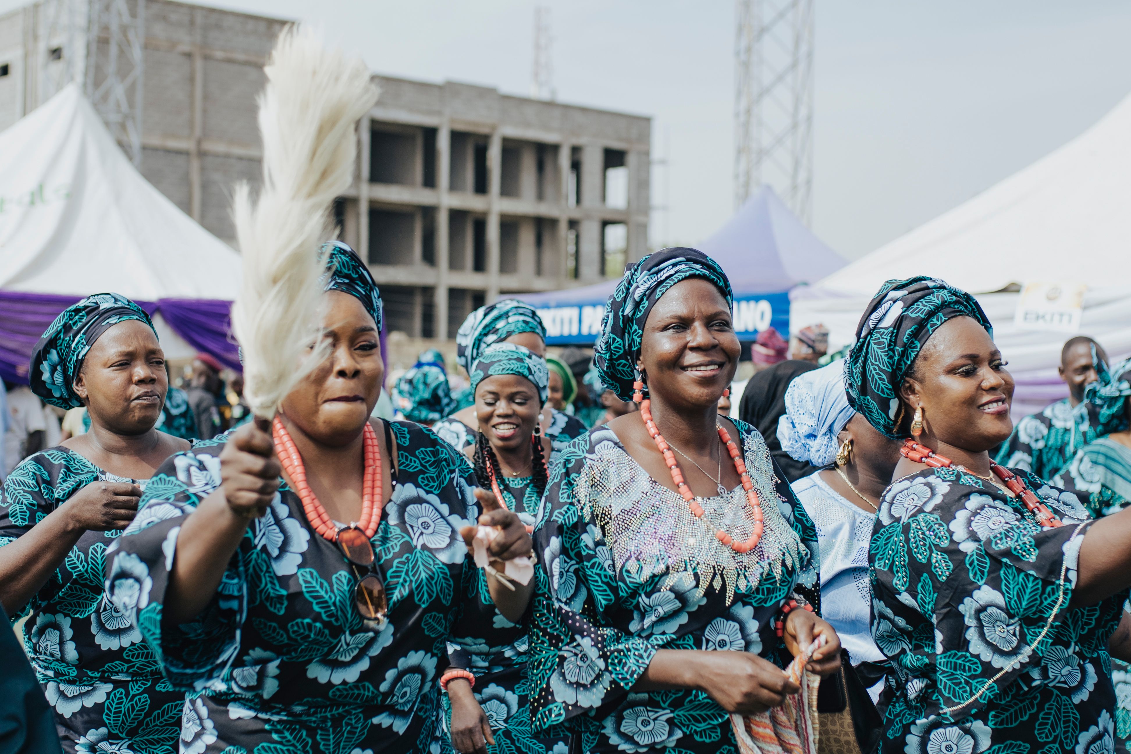 Joyful group of African women in traditional attire participating in a cultural celebration outdoors.