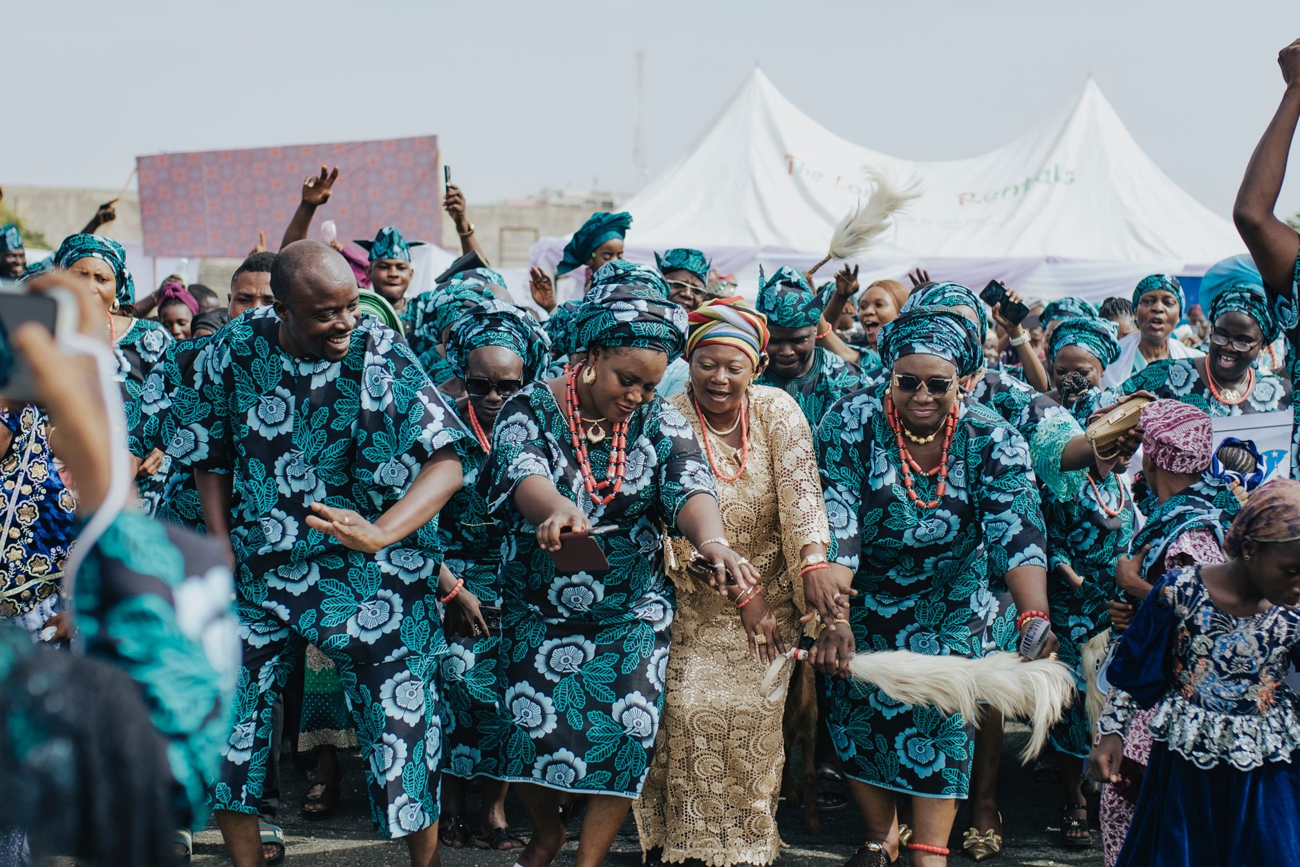 Group of people in traditional African attire dancing joyfully outdoors.