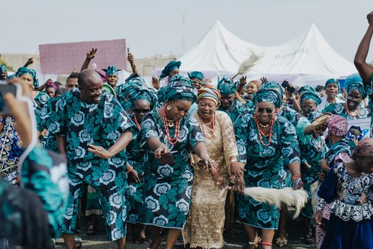 Group of people in traditional African attire dancing joyfully outdoors.