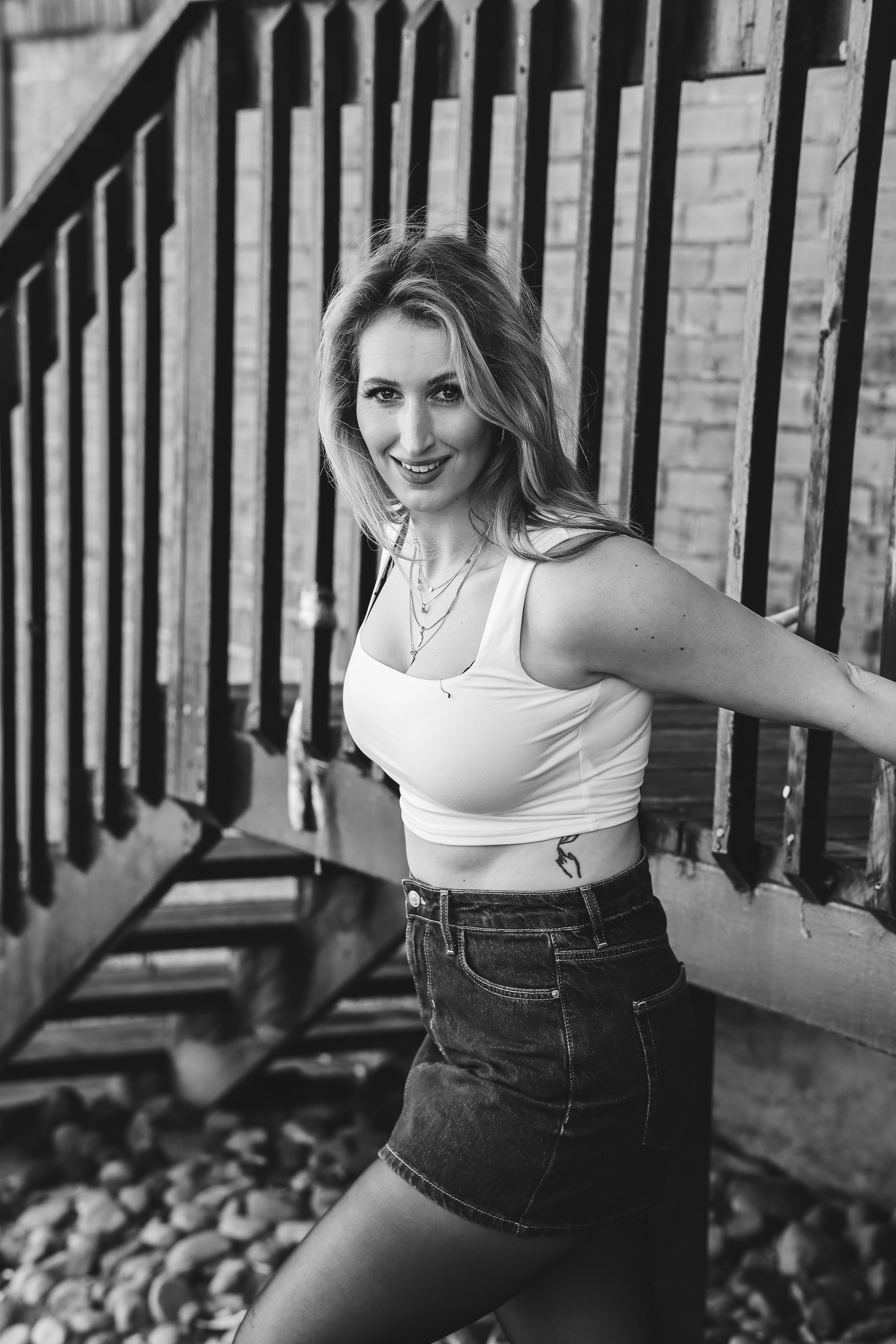 Elegant black and white portrait of a stylish woman posing by a staircase, exuding confidence and charm.