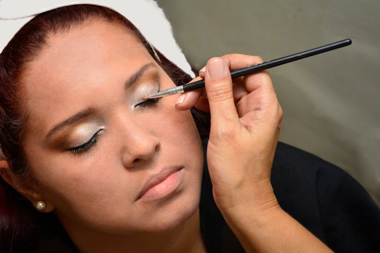 Person Putting Makeup On The Face Of A Woman 