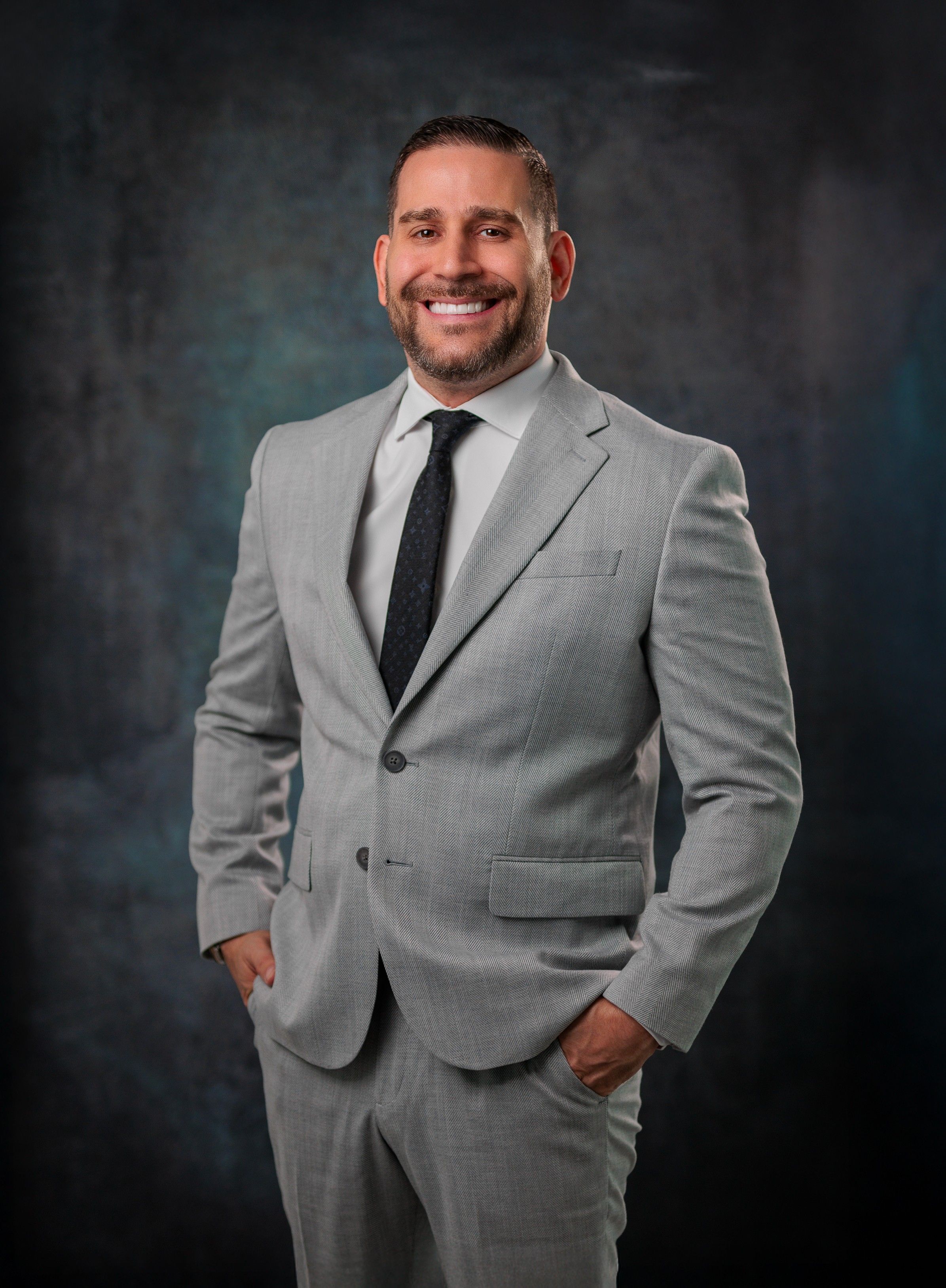 Business portrait of a smiling man in a gray suit, perfect for corporate profiles and professional contexts.