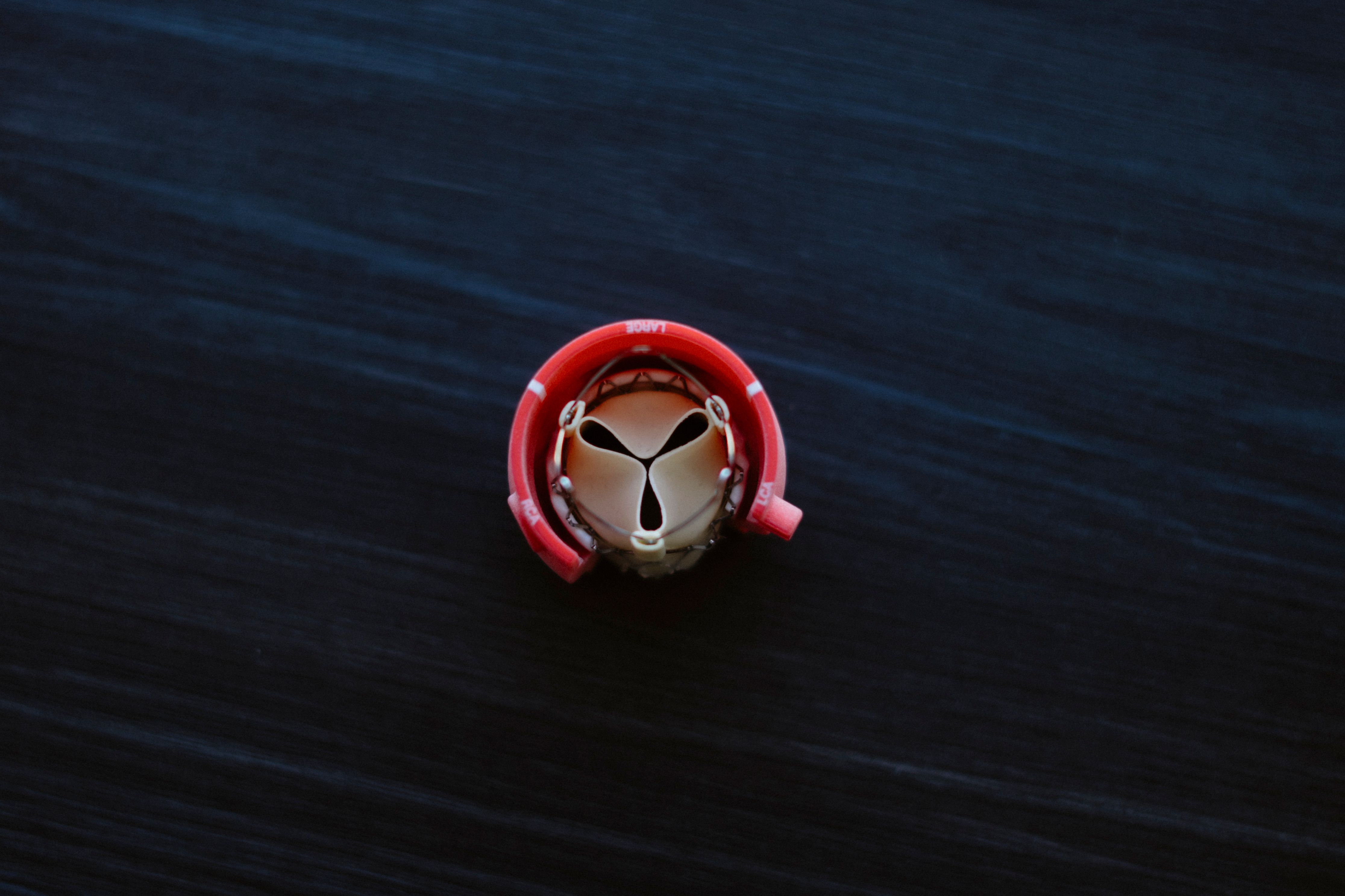 Close-up of a compact red rotary tool on a dark background.