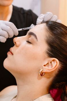 Close-up of woman receiving cosmetic injection, enhancing facial features.