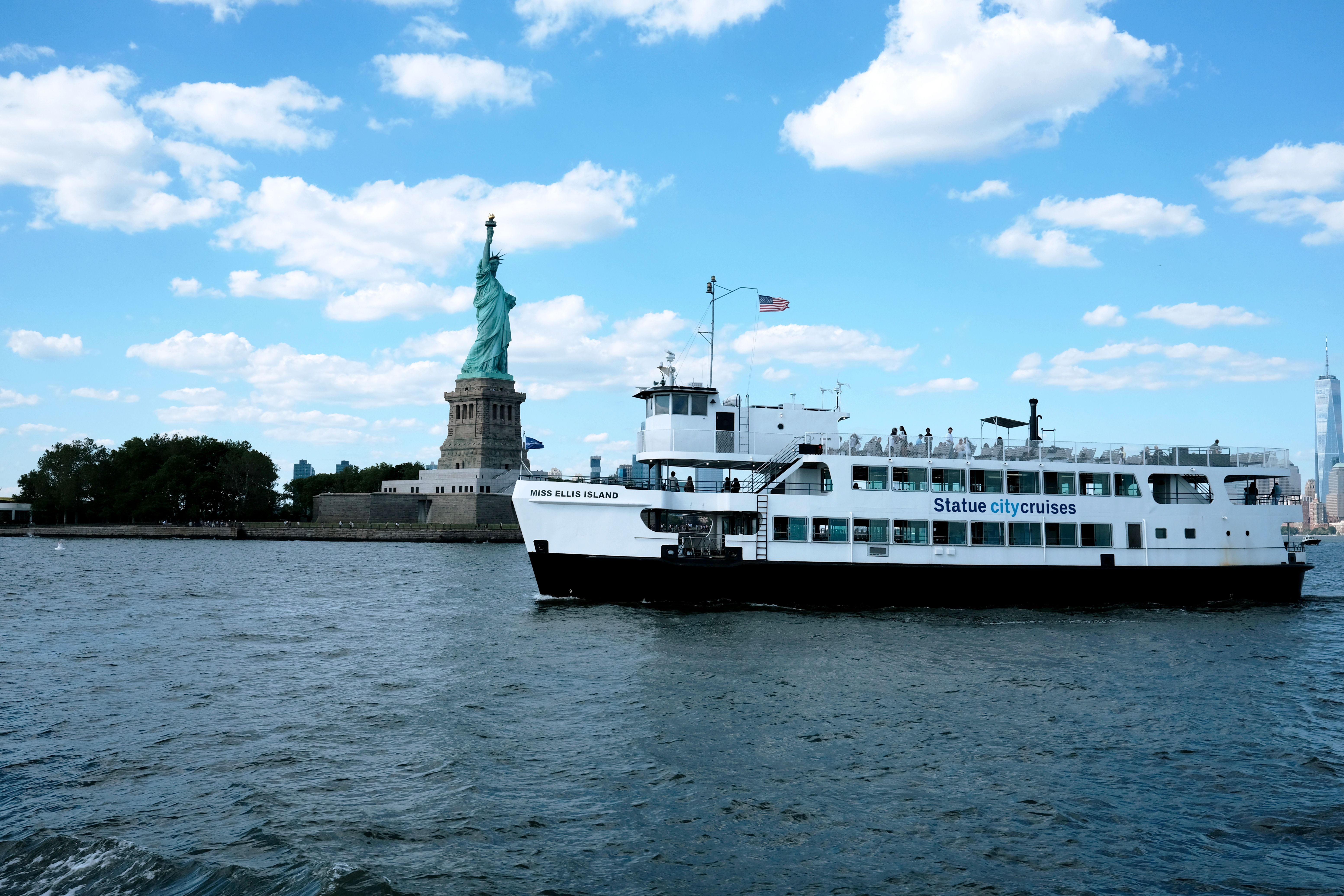 Unbeatable New York Afternoon Fall Foliage Cruise with Lunch Review: A Stunning Hudson River Escape Review 2026 - Scenic view of the Statue of Liberty and ferry boat in Jersey City under a bright summer sky.