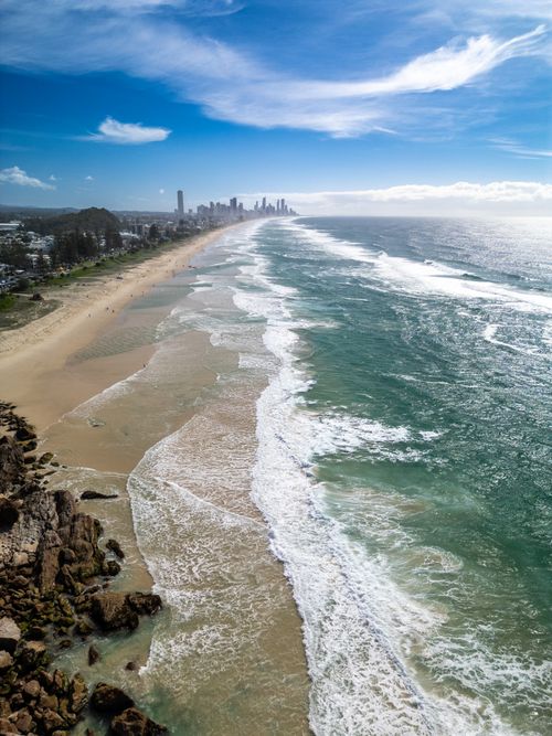 Free Stunning aerial view of Gold Coast shoreline with city skyline in the distance, vibrant seas. Stock Photo