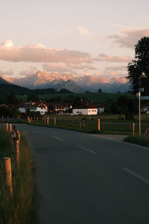Free Charming alpine village with mountain backdrop in warm sunset light. Stock Photo