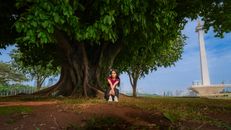 Woman sitting under tree near the National Monument in Jakarta.