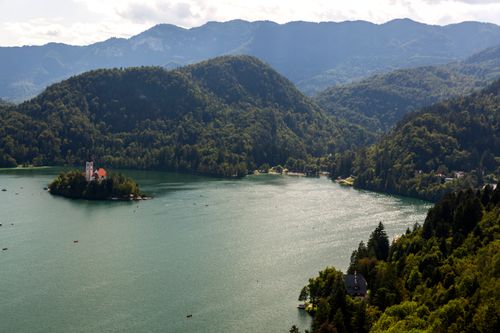 Free Aerial shot of Lake Bled with a picturesque island and church, surrounded by mountains. Stock Photo