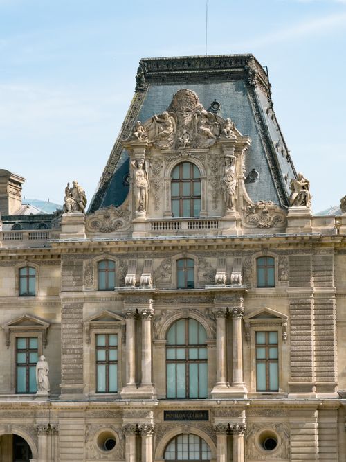 Free Close-up view of the intricate architectural facade of the Louvre Museum in Paris featuring classic sculptures. Stock Photo
