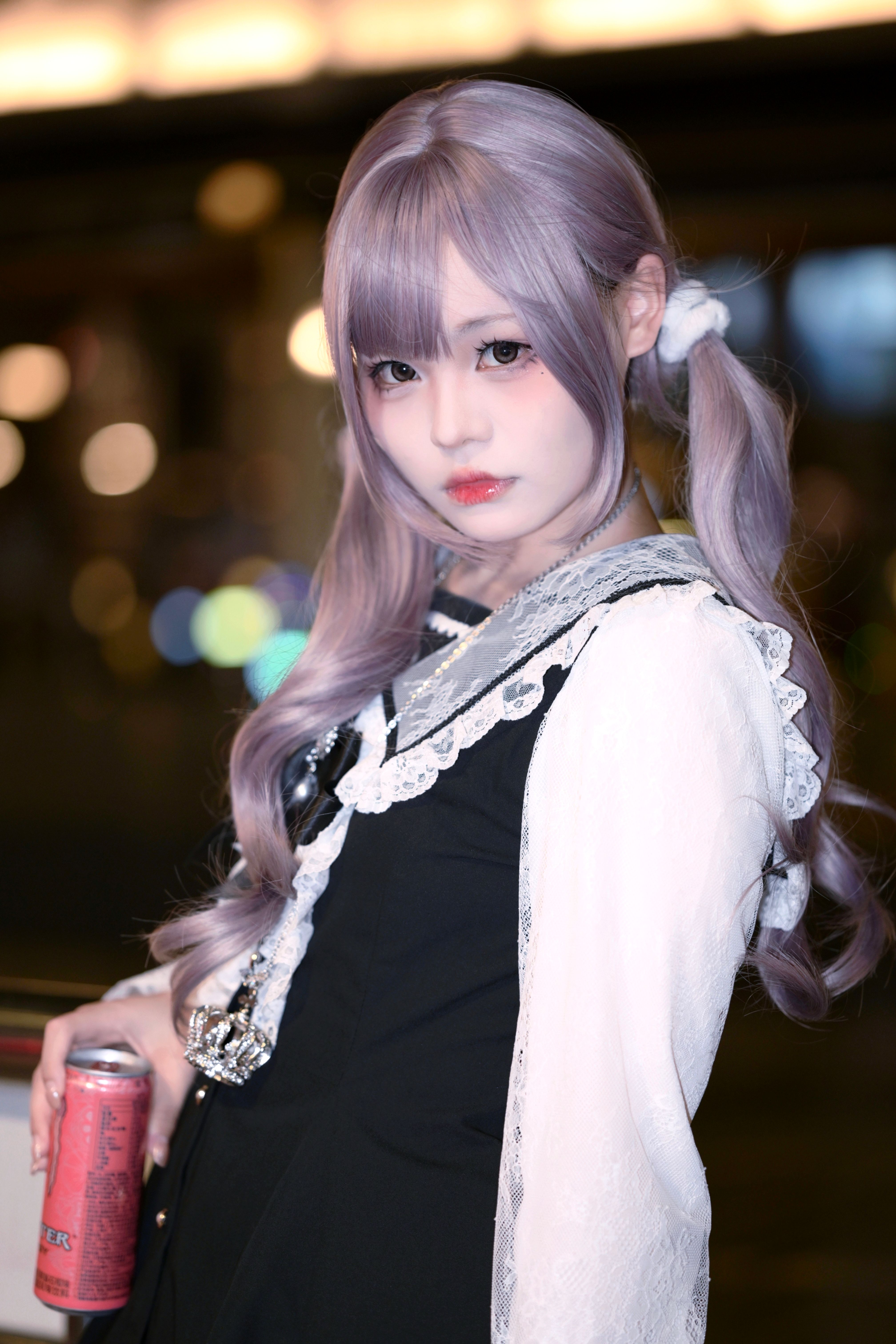 Stylish woman with silver hair posing at night in a fashionable outfit, holding a can.