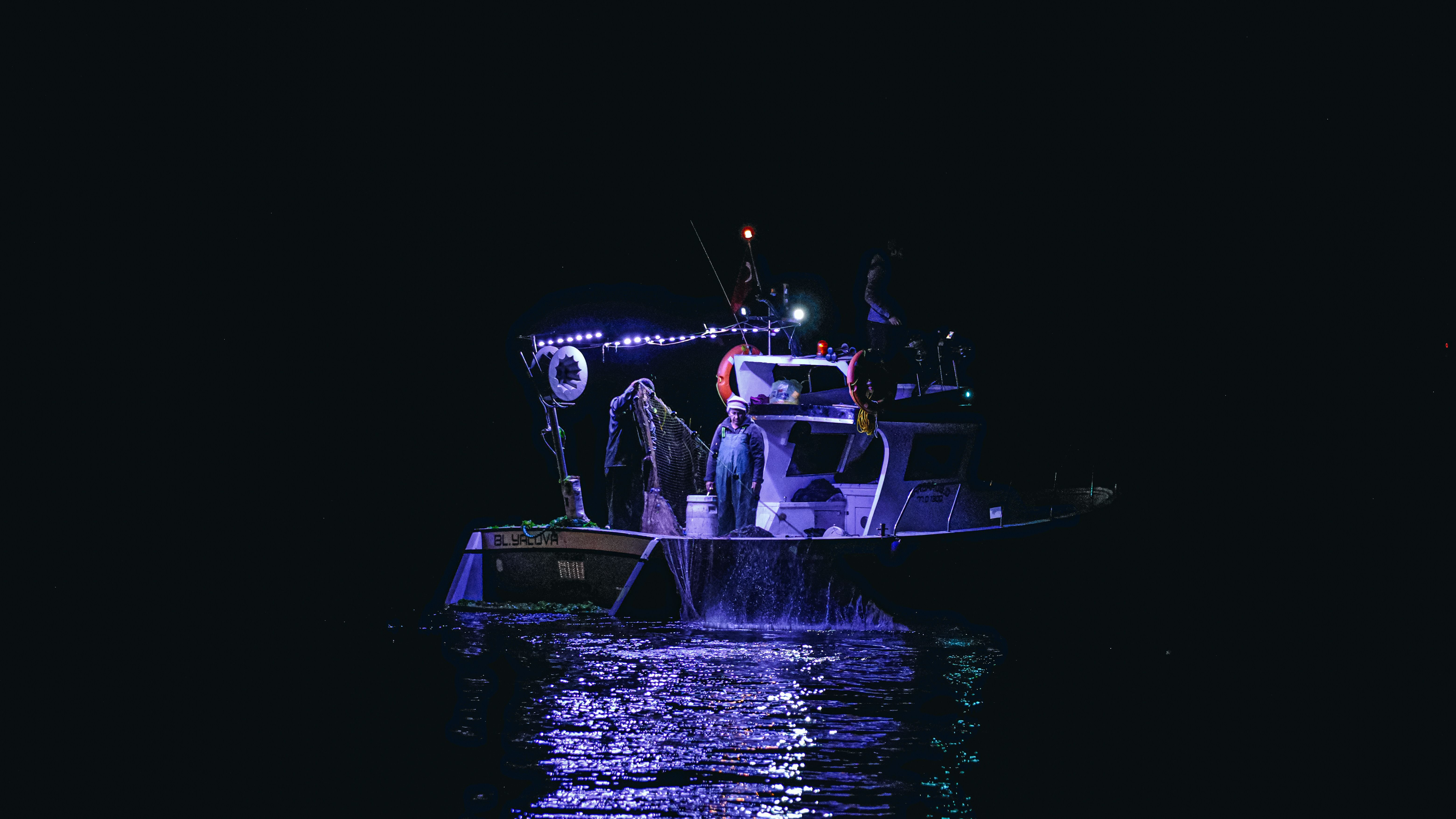 Barca de pesca iluminada de noche en mar abierto, imagen ilustrativa de las travesías nocturnas desde Ceuta