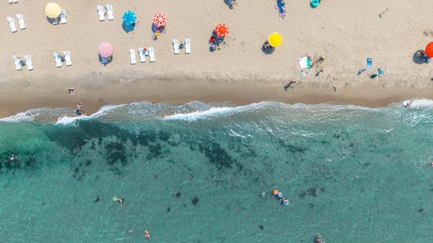 Aerial beach scene with vibrant umbrellas and clear blue water