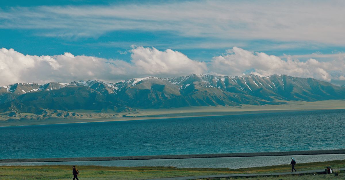 Viajero con el móvil y una eSIM ante las montañas y un lago de Kirguistán