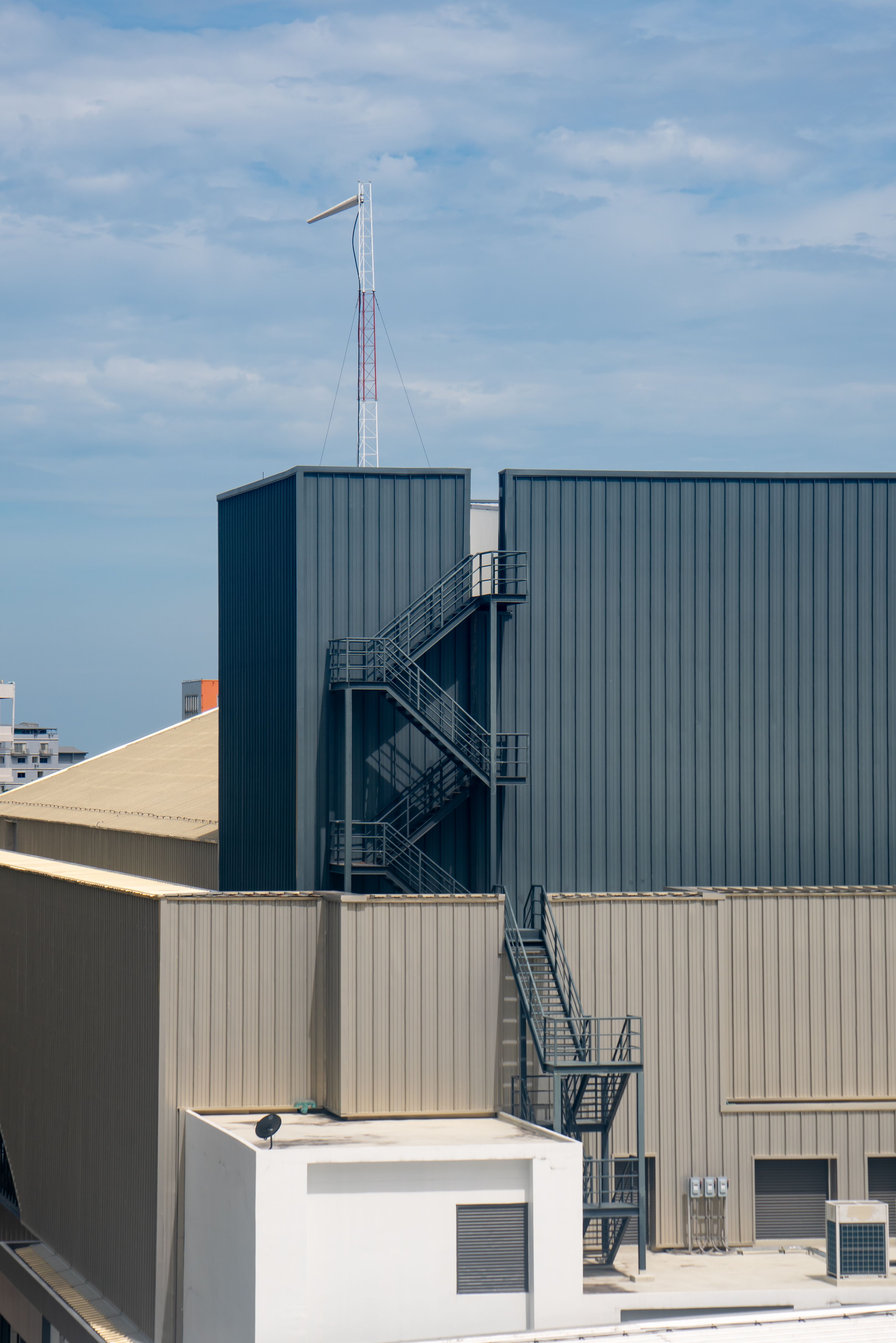 Commercial building rooftop with an outside metal staircase under a clear sky