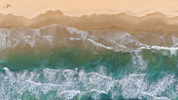 A stunning aerial shot of Queensland's beach showcasing the beautiful ocean waves meeting the shore.