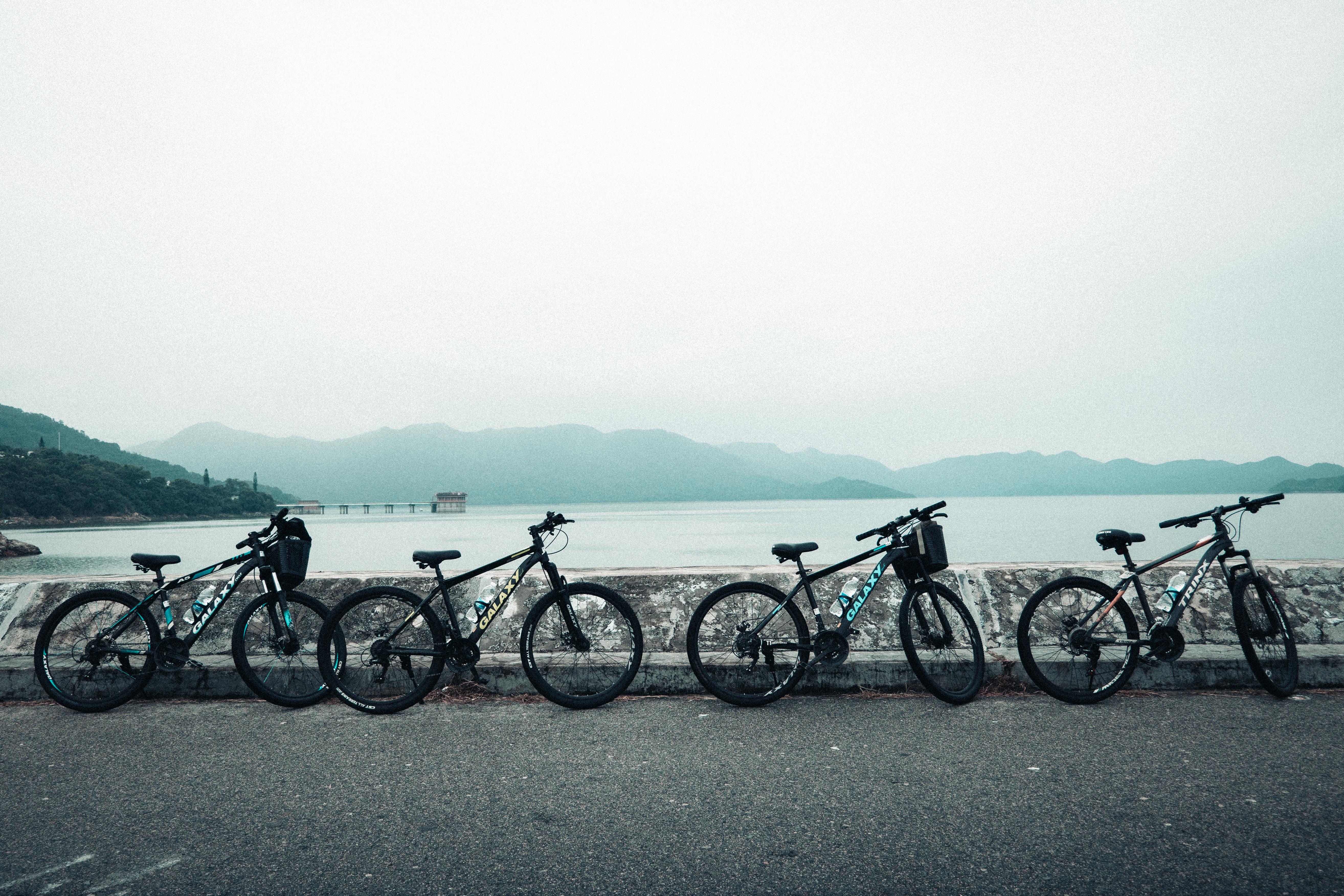 Five mountain bikes lined up by a peaceful lake in New Territories, Hong Kong.