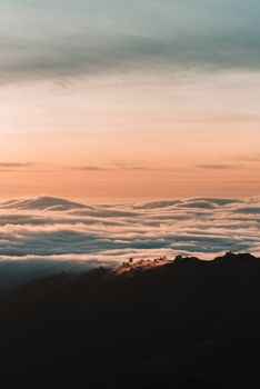 日落时分，色彩缤纷，云层之上山脉宁静，营造出一派平静而风景如画的景象