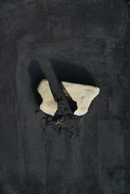 Broken stone pieces on a dark surface creating a conceptual minimalist still life shot.
