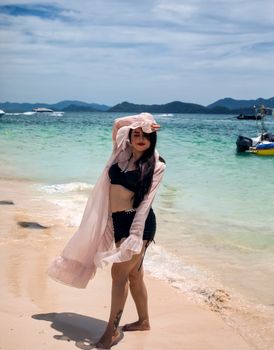 A woman enjoying a sunny beach day, posing in swimwear with tropical islands in the background.