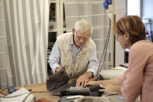 Senior male artisan creating bag together with female assistant
