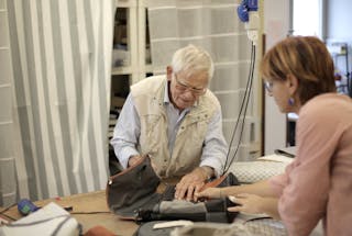 Senior male artisan creating bag together with female assistant