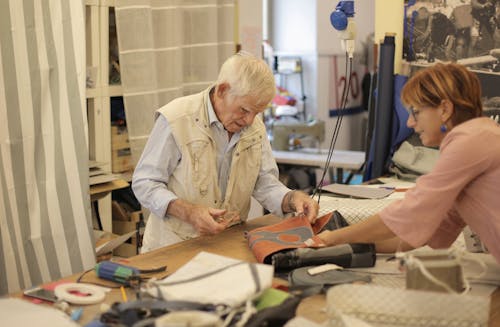 Artigiano Invecchiato Che Fa Borsa In Pelle In Officina Con Assistente