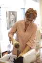 Concentrated mature female master in casual wear installing magnetic button using tools while adding details on handmade bag