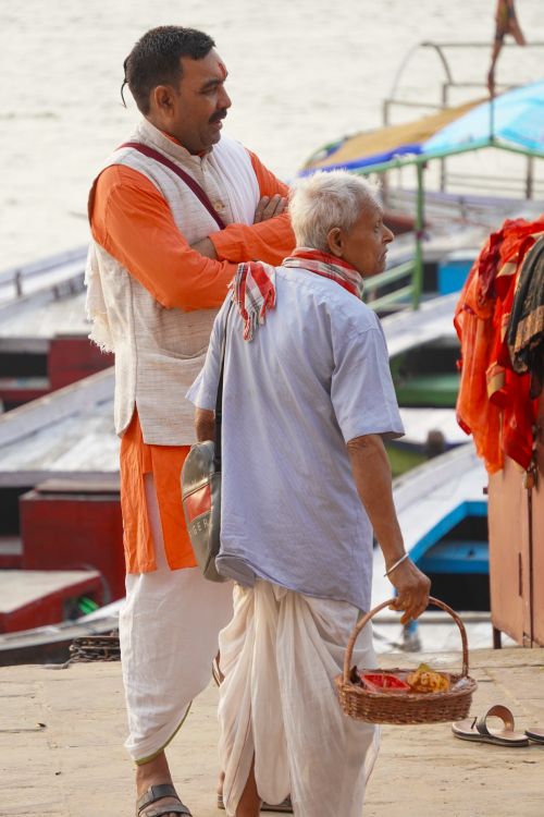 Free Two men engage in conversation by the Ganges River in Varanasi, India, showcasing traditional attire. Stock Photo