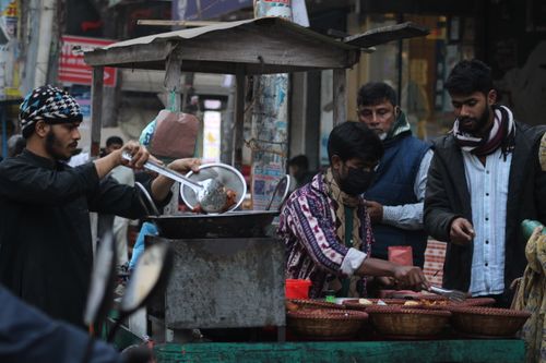 Free Street food vendors preparing and serving meals in a bustling urban market setting. Stock Photo