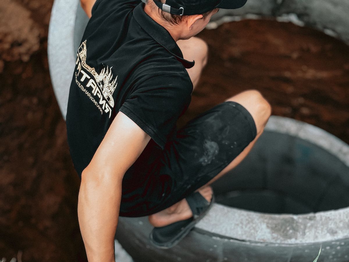 Construction worker installing a concrete well segment outdoors