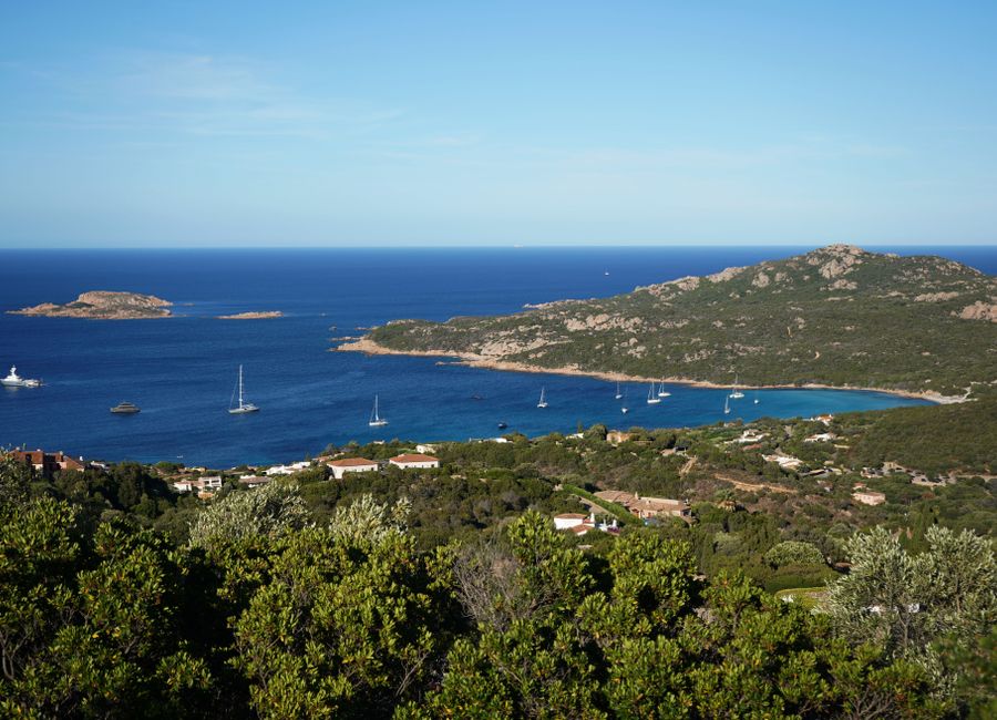 Beautiful panoramic view of Sardinia's coastline with clear blue waters and lush greenery.
