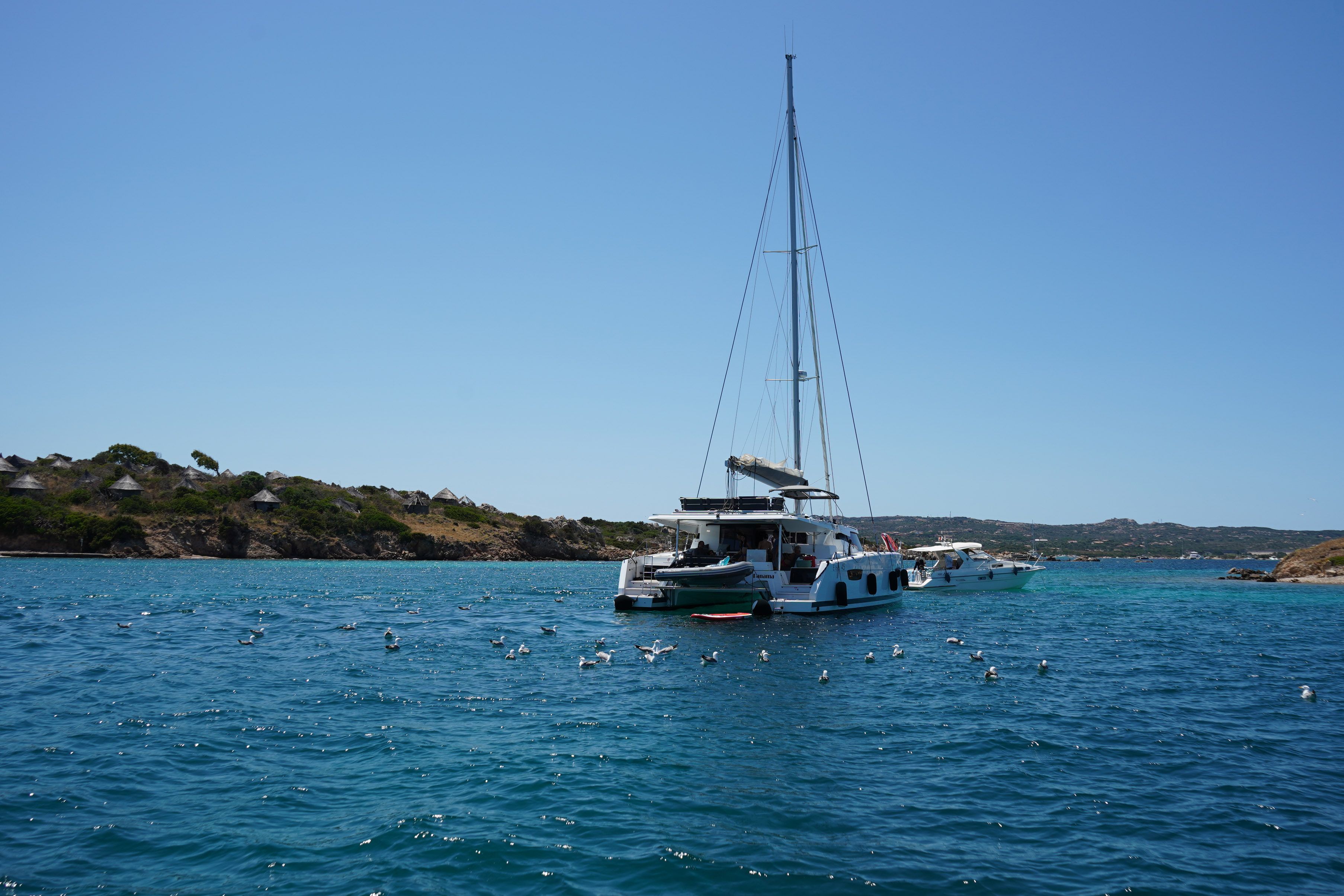 Stunning Cefalù : Mini Yacht Tour with Aperitif, Snorkeling and Caves Review 2026 - A yacht peacefully anchored in the clear blue waters off the coast of Sardinia, Italy.