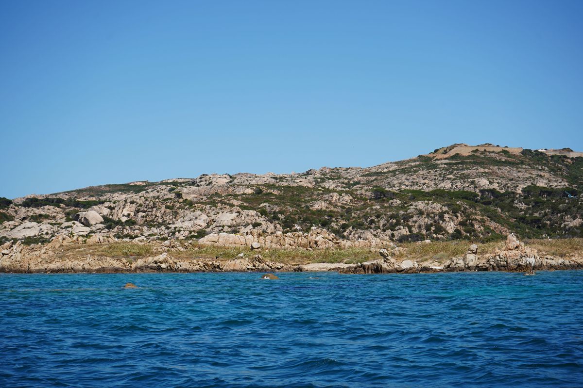 Insula joasa de granit cu iarba uscata si o casa alba