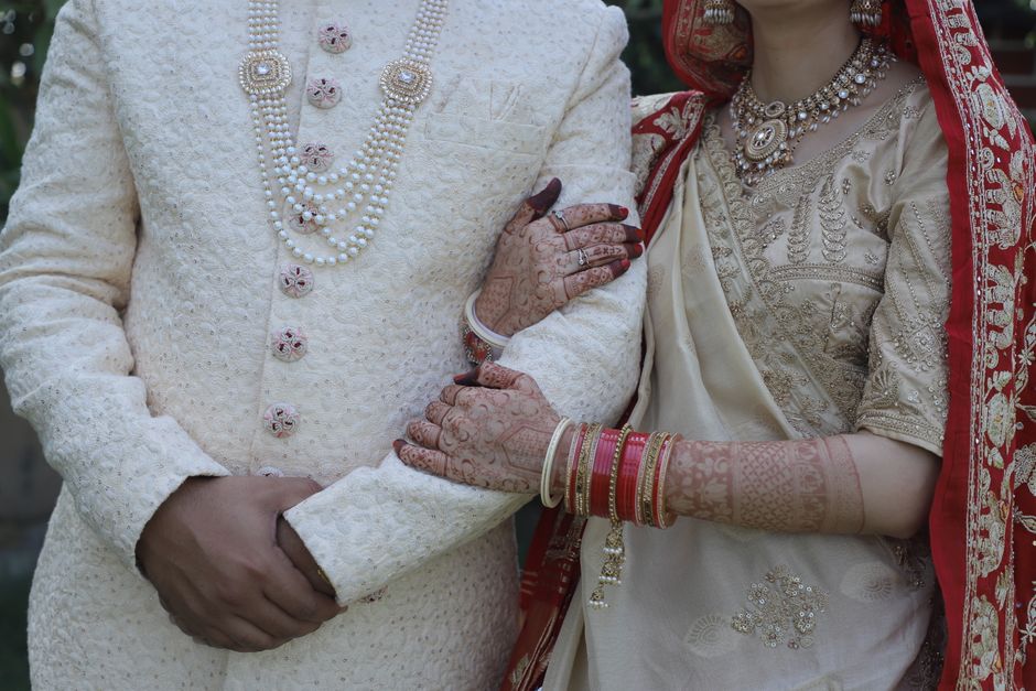 Close-up of an Indian couple in traditional wedding attire during an outdoor ceremony.
